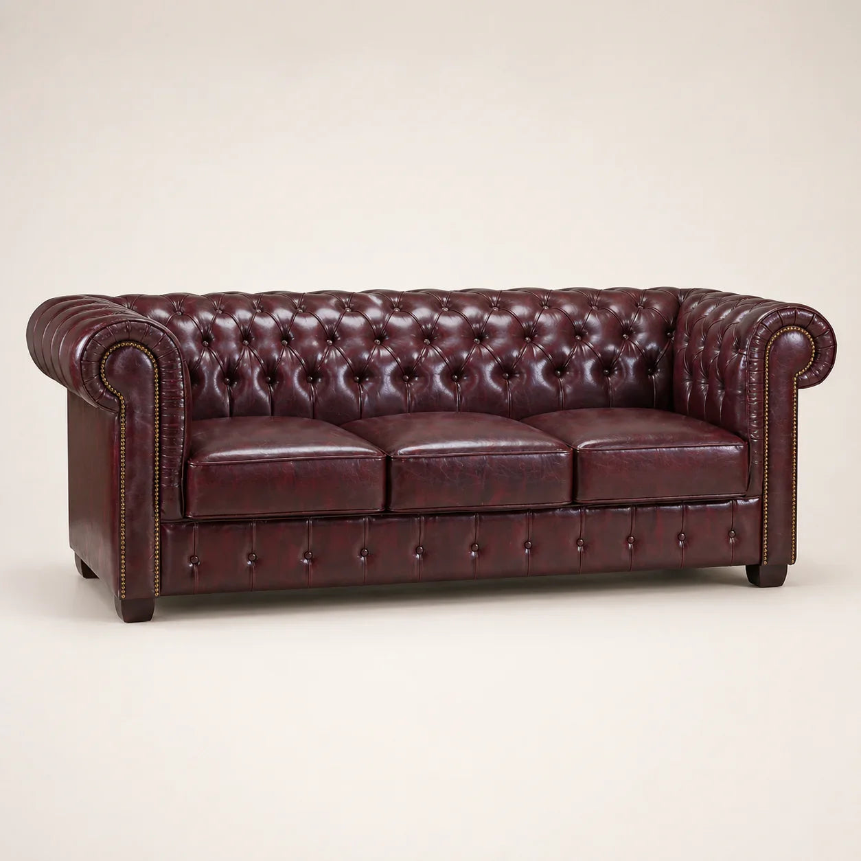 Luxury burgundy leather Chesterfield sofa with tufted back and rolled arms, ideal for elegant living rooms.