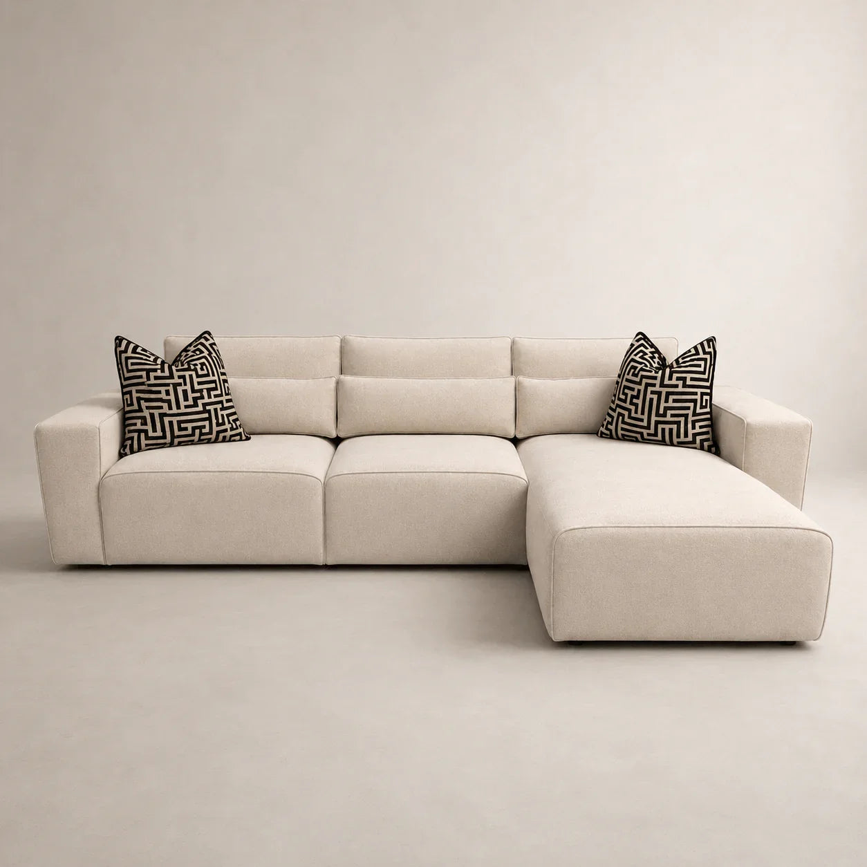 Beige L-shaped sectional sofa with geometric black and white pillows, modern luxury living room furniture