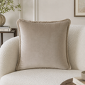 Beige velvet throw pillow with fringe on a textured sofa, luxury home decor accent