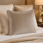 Luxury beige velvet throw pillow with fringe on a styled bed, perfect for cozy bedroom decor.