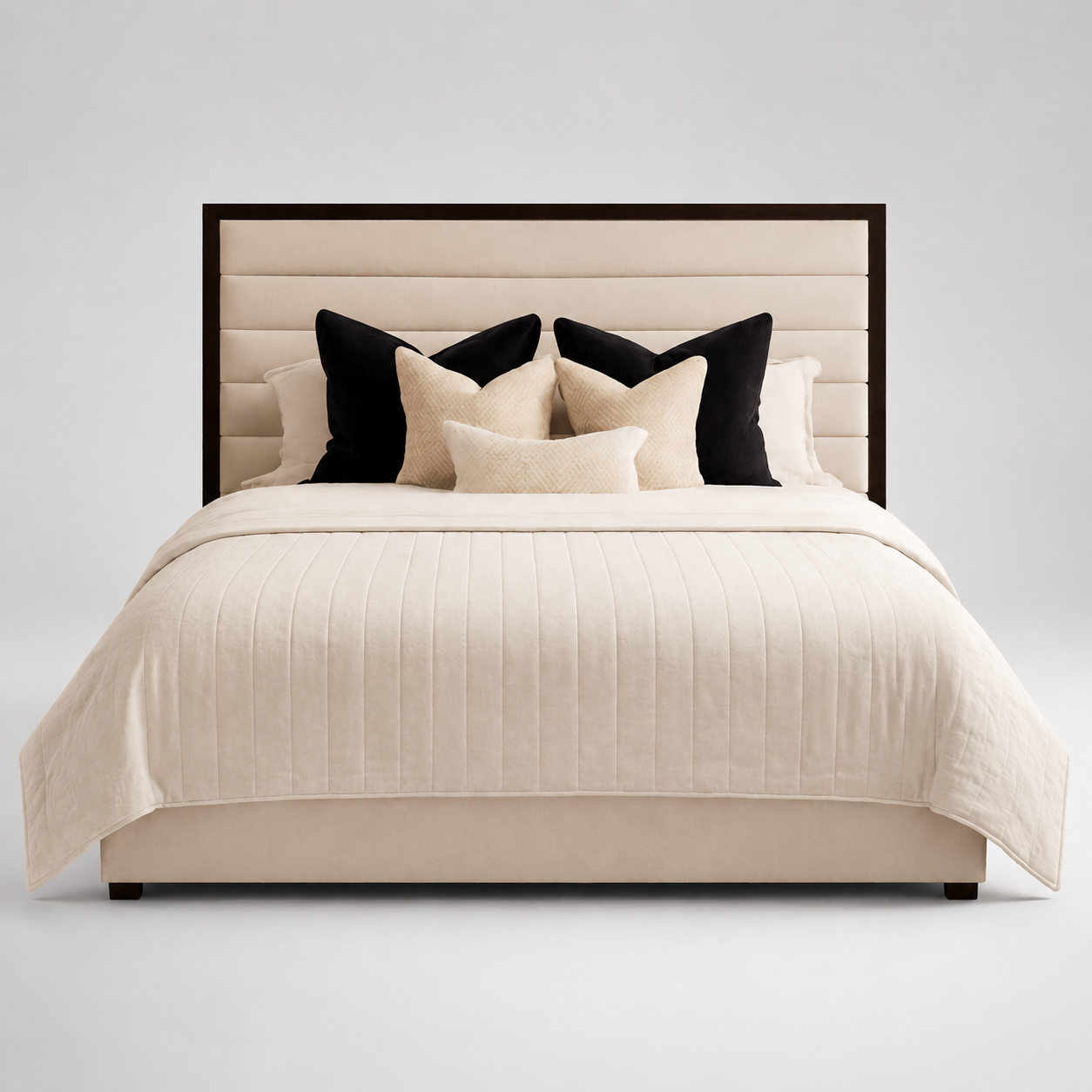 Luxury beige upholstered bed with tufted headboard, black and cream pillows, and quilted bedding