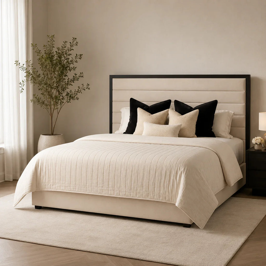 Luxury upholstered bed with tufted headboard, cream quilted bedding, and black accent pillows in modern bedroom