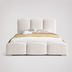 Luxury upholstered bed with segmented headboard and footboard, white bedding, gold throw
