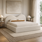 Luxury upholstered bed with curved headboard in neutral tones, styled in modern bedroom with bedside tables and art