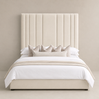 Luxury beige upholstered bed with tall tufted headboard, white linens, and decorative pillows