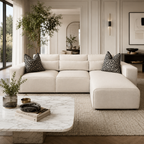 Luxury beige sectional sofa with geometric pillows in modern living room, marble coffee table, and large windows