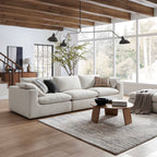 Large beige sectional sofa with ottoman in modern living room, wooden coffee table, and rug