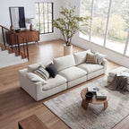 Modern living room with beige extended sofa and ottoman, large windows, and neutral decor