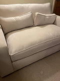 Modern beige fabric sofa with two matching rectangular cushions in a living room