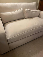 Modern beige fabric sofa with two matching rectangular cushions in a living room