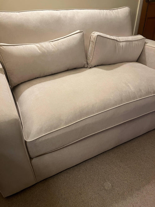 Modern beige fabric sofa with two matching rectangular cushions in a living room