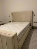 Modern beige upholstered bed with tall headboard in a minimal bedroom setting