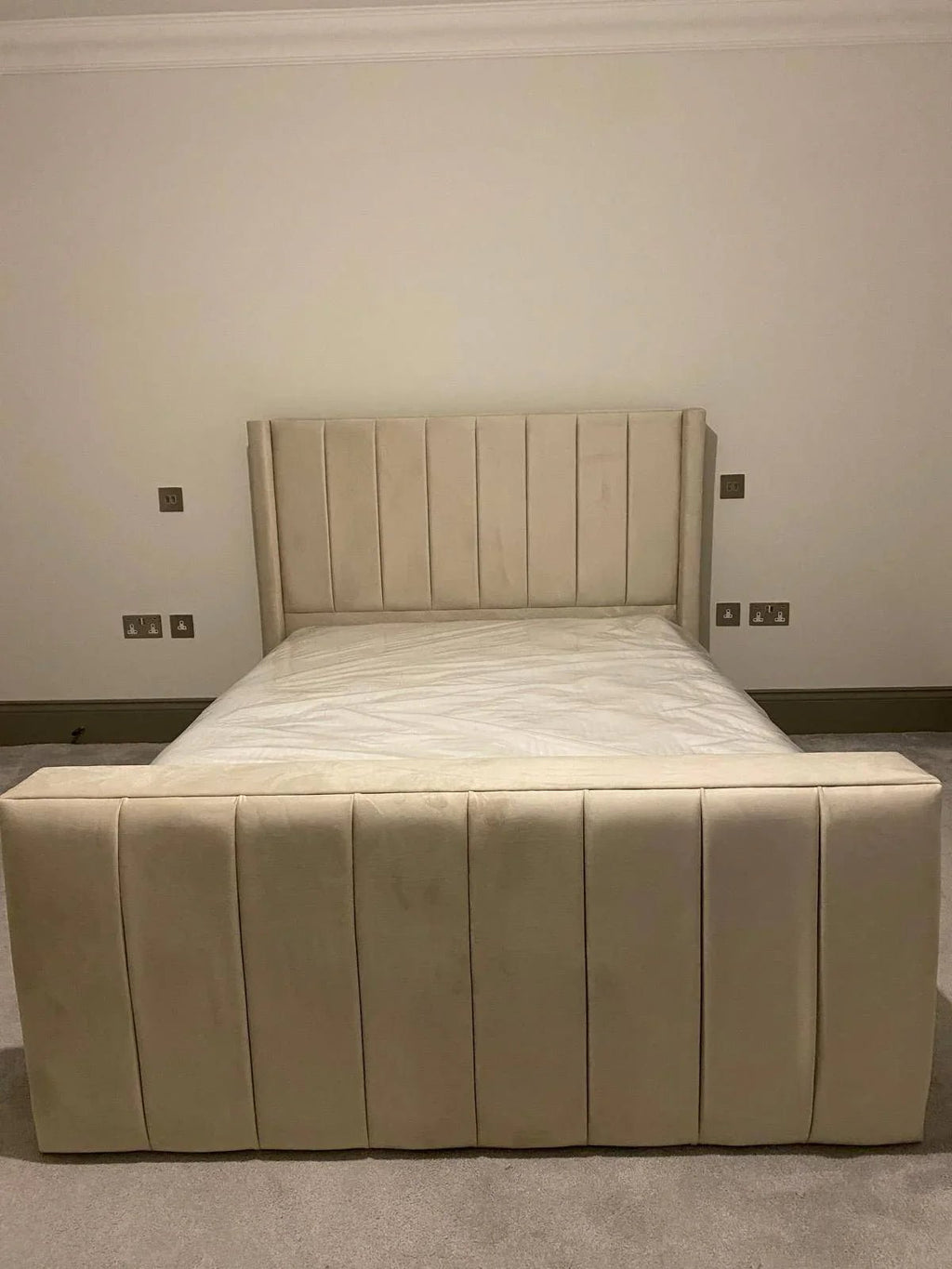 Beige upholstered bed with vertical panel headboard and footboard in a modern bedroom