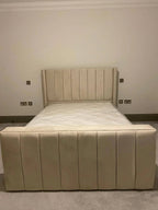 Beige upholstered bed with vertical panel headboard and footboard in a modern bedroom
