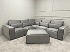Modern grey corner sectional sofa with matching ottoman in a minimalist living room