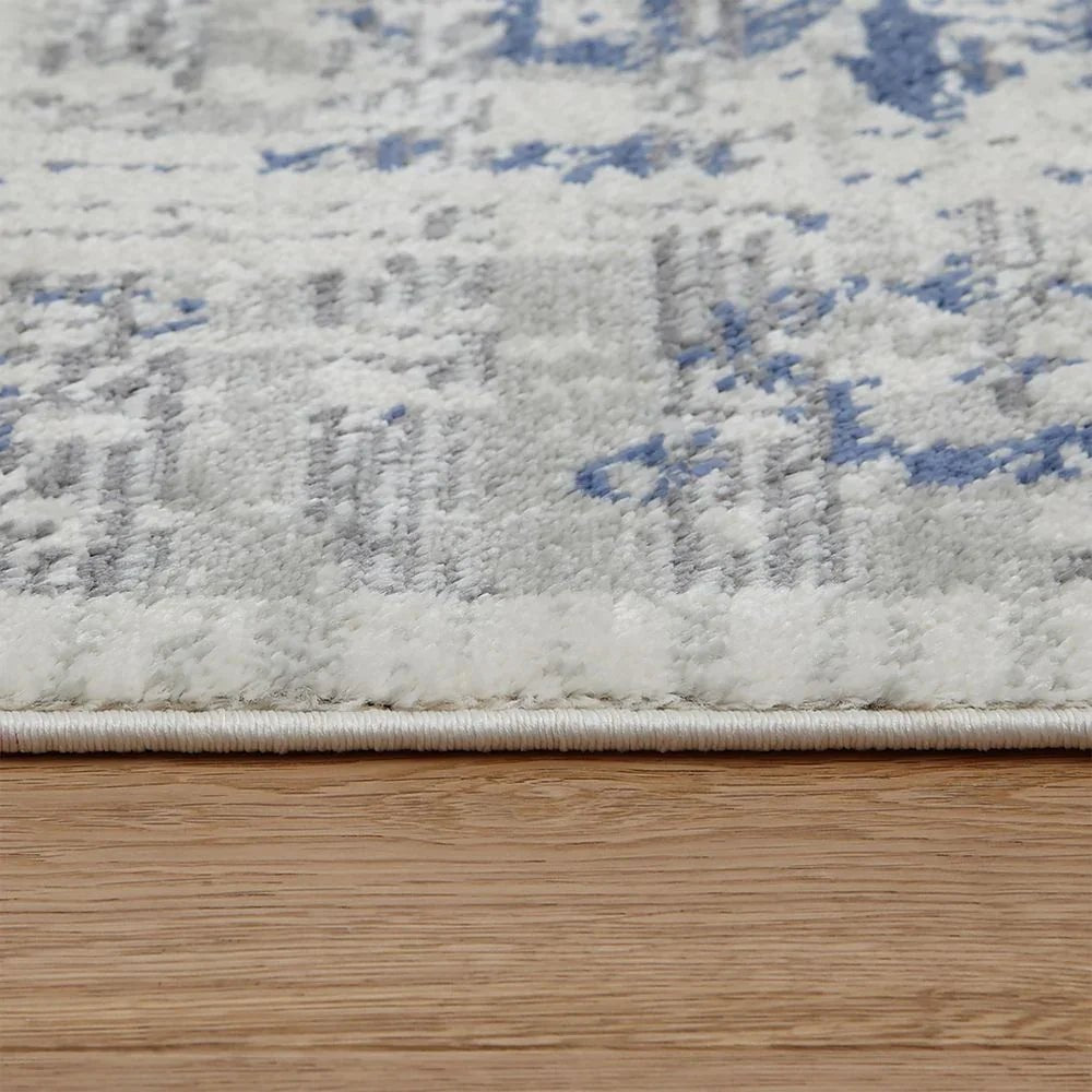 Soft blue and white patterned area rug on hardwood floor, plush texture detail