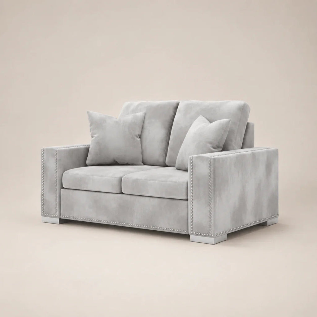 Luxury gray velvet two-seater sofa with nailhead trim and matching cushions, ideal for modern living rooms.