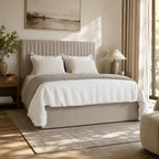 Luxury upholstered bed with tufted headboard, white linens, and neutral bedroom decor