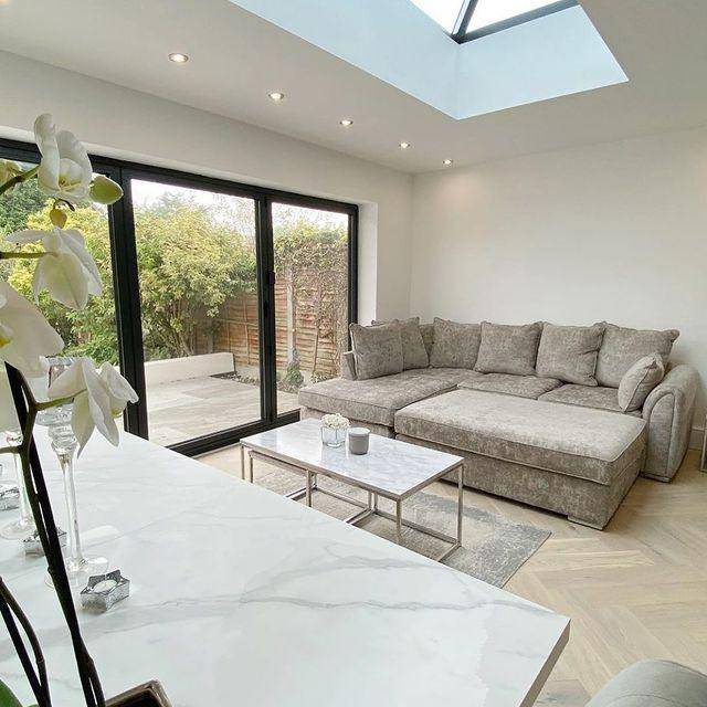 Modern living room with grey corner sofa bed, marble coffee table, and large windows