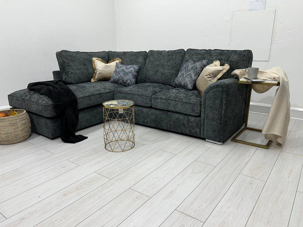 Dark grey corner sofa bed with scatter cushions in modern living room, side table and blanket