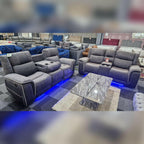 Grey microfibre electric recliner 3 and 2 seater sofa set with blue LED lighting beside marble coffee table in showroom.