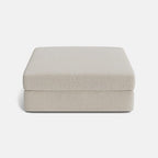 Beige modular ottoman with cushioned top, minimalist design, isolated on white background.