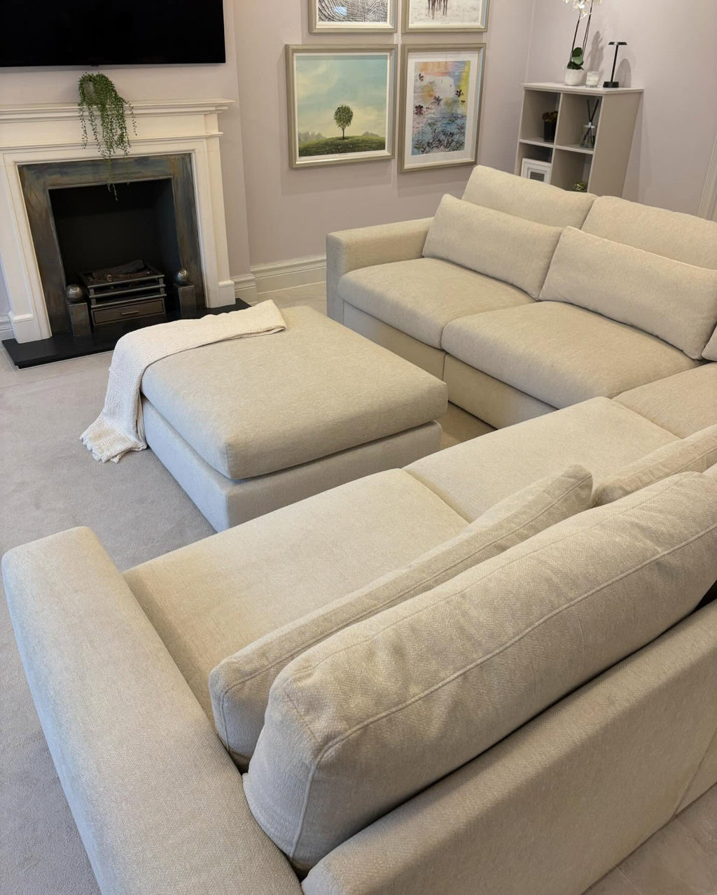 Beige modular corner sofa set with matching ottoman in a modern living room