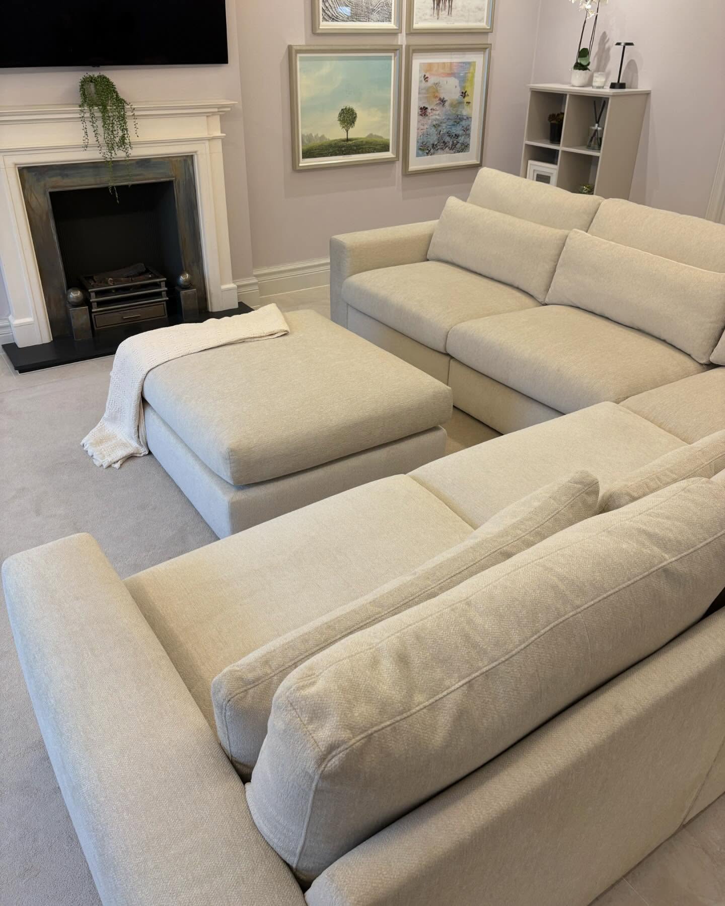 Beige modular corner sofa set with matching ottoman in a modern living room