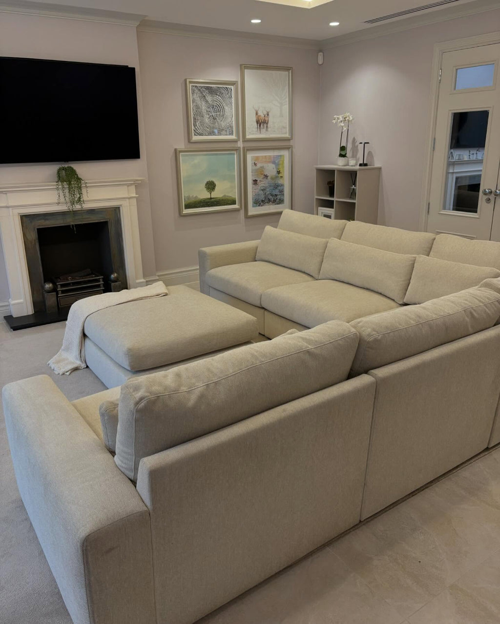 Modern living room with a beige 4-piece modular corner sofa and matching ottoman