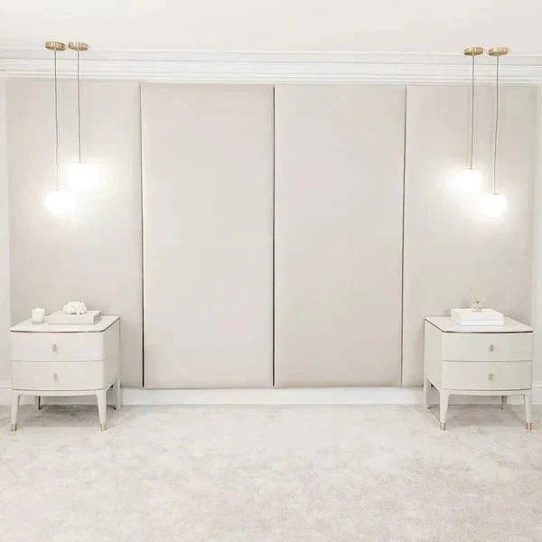 Cream velvet upholstered headboard wall panels with modern bedside tables and pendant lights