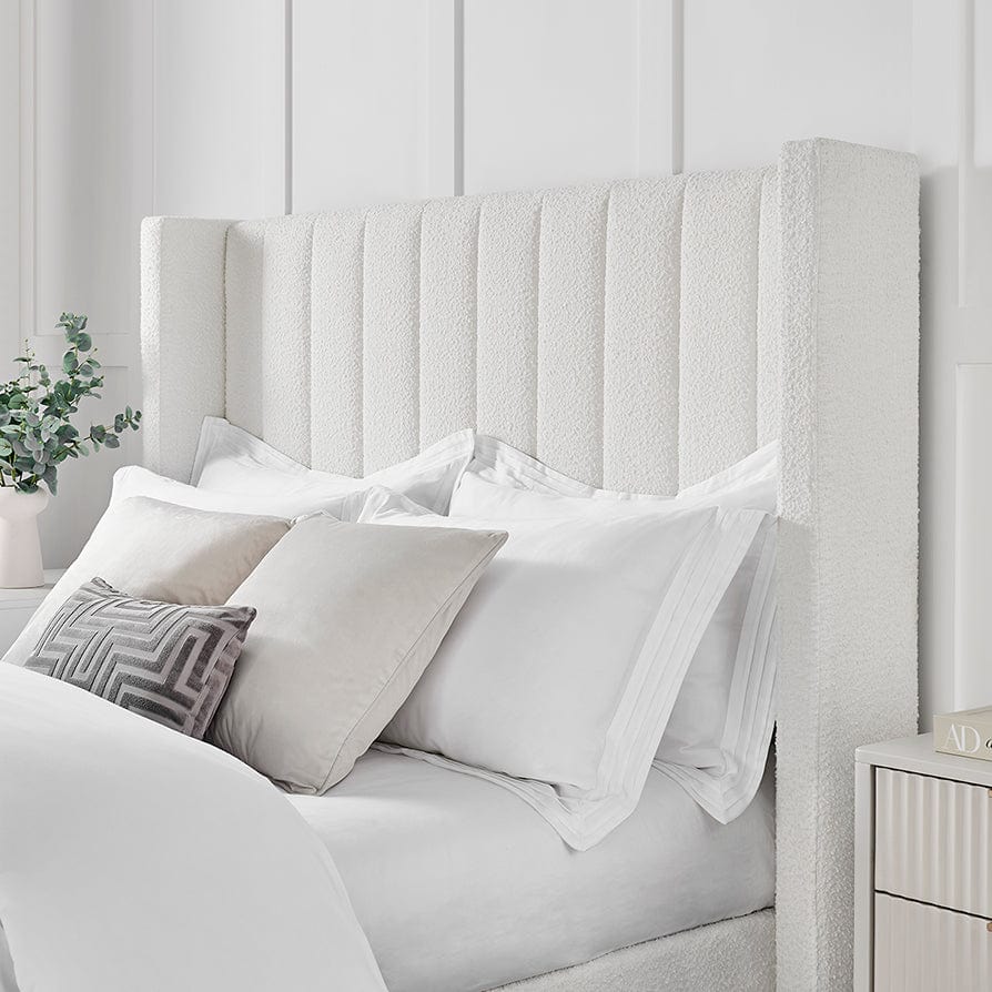 Bouclé fabric ottoman storage bed with tall fluted headboard and neutral bedding in modern bedroom