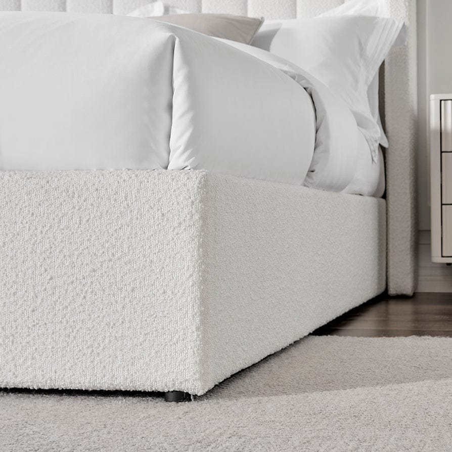 Modern double bed with white boucle ottoman storage base and crisp bedding in a bright bedroom
