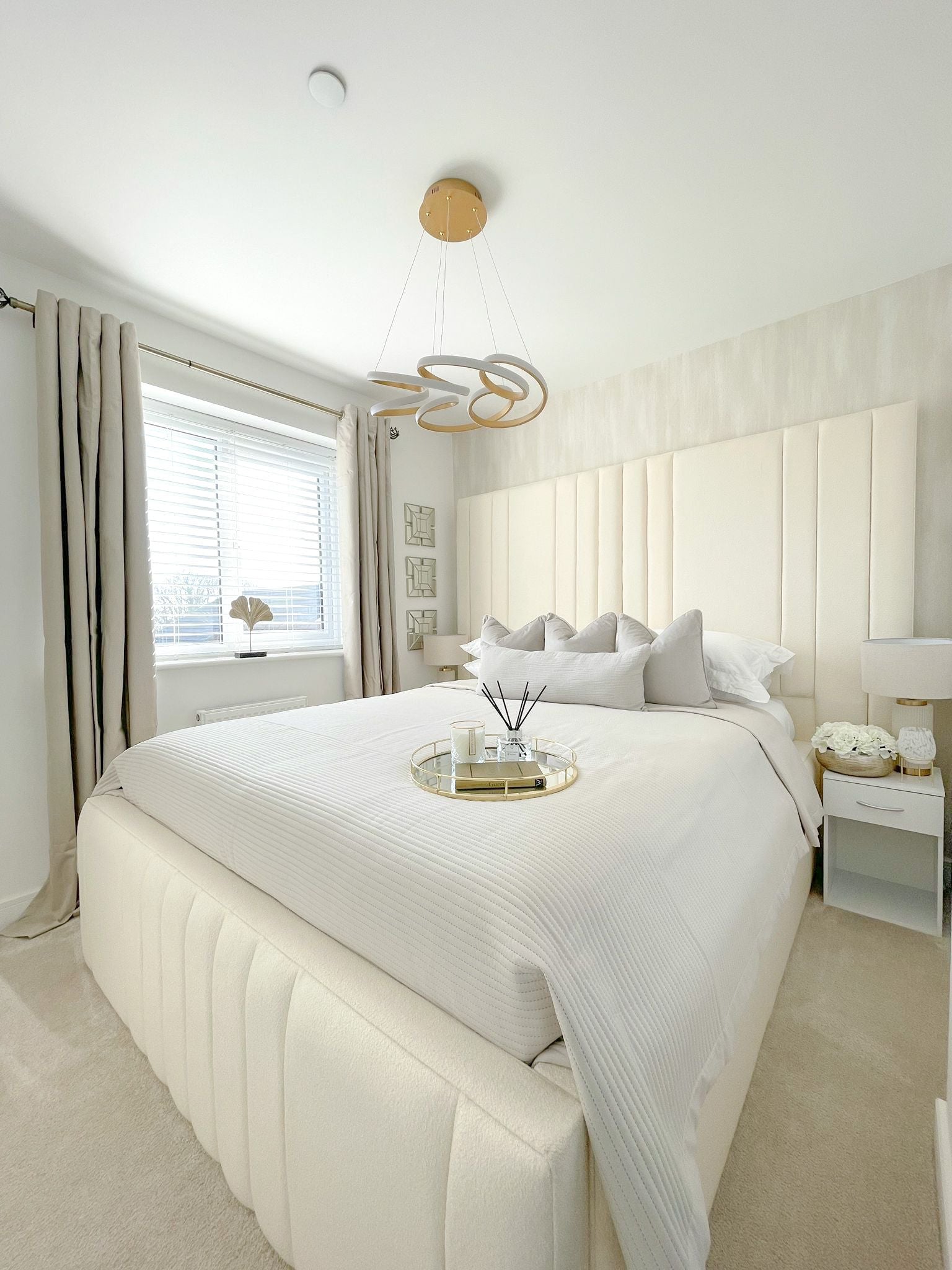 Modern double bed with boucle upholstery in a bright, minimalist bedroom with neutral decor.