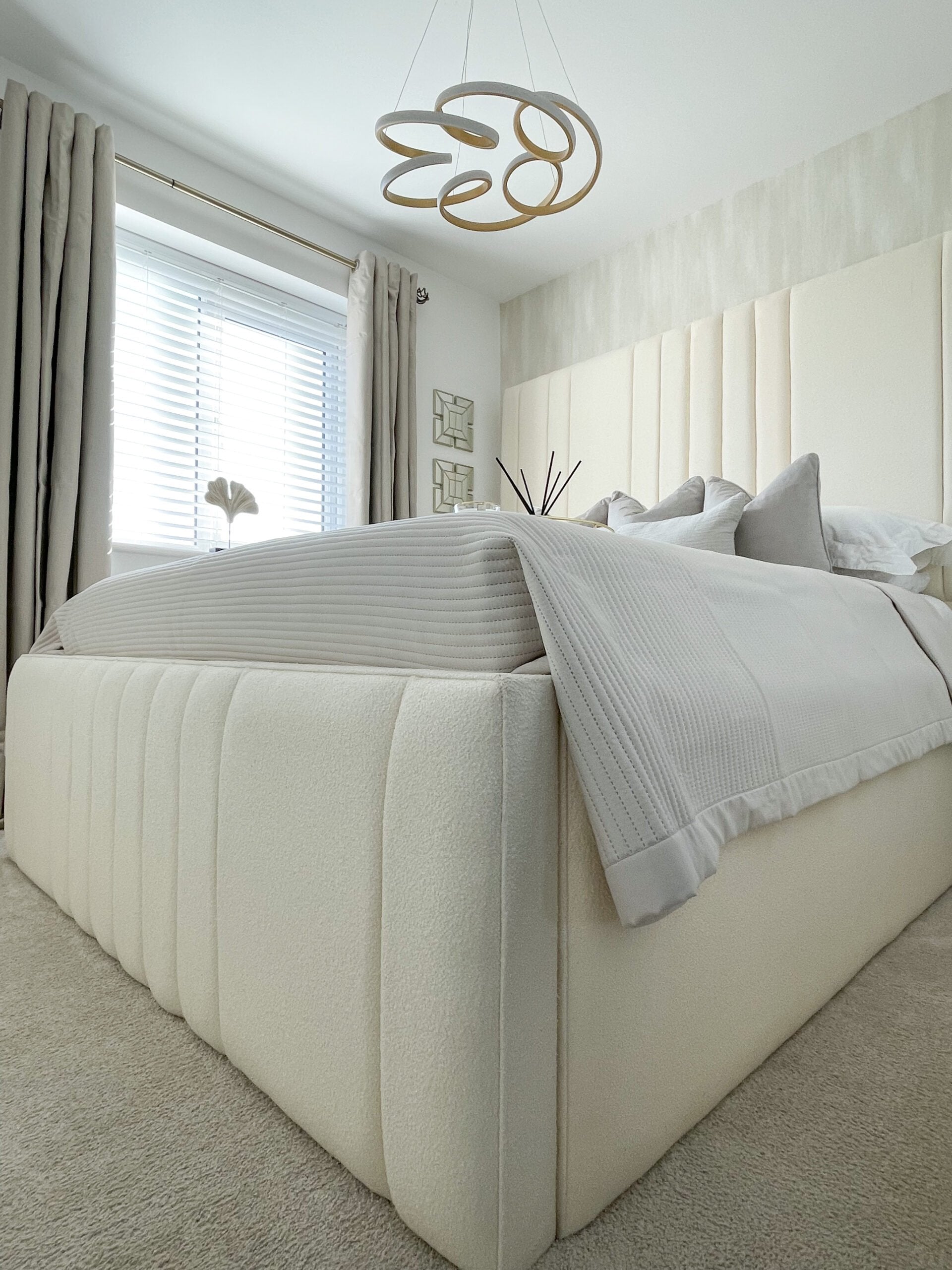Modern double bed with cream boucle upholstery and headboard in a bright bedroom