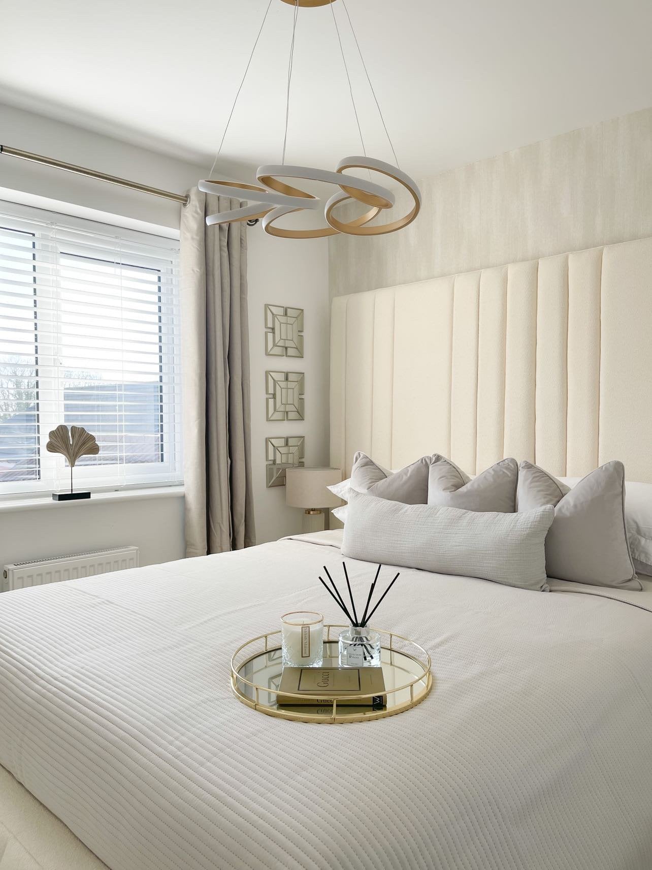Modern double bed with cream boucle headboard, neutral bedding, and decorative tray in a bright bedroom.