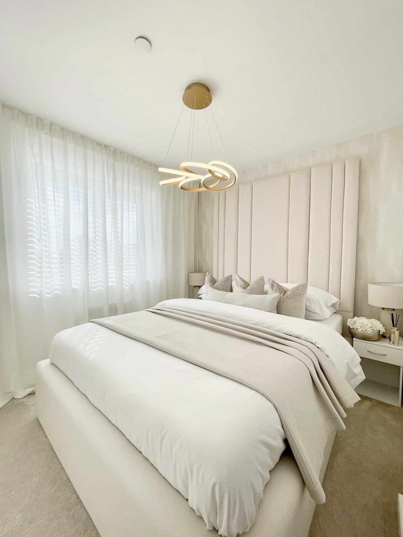 Modern cream upholstered double bed with tall headboard in a bright, minimalist bedroom