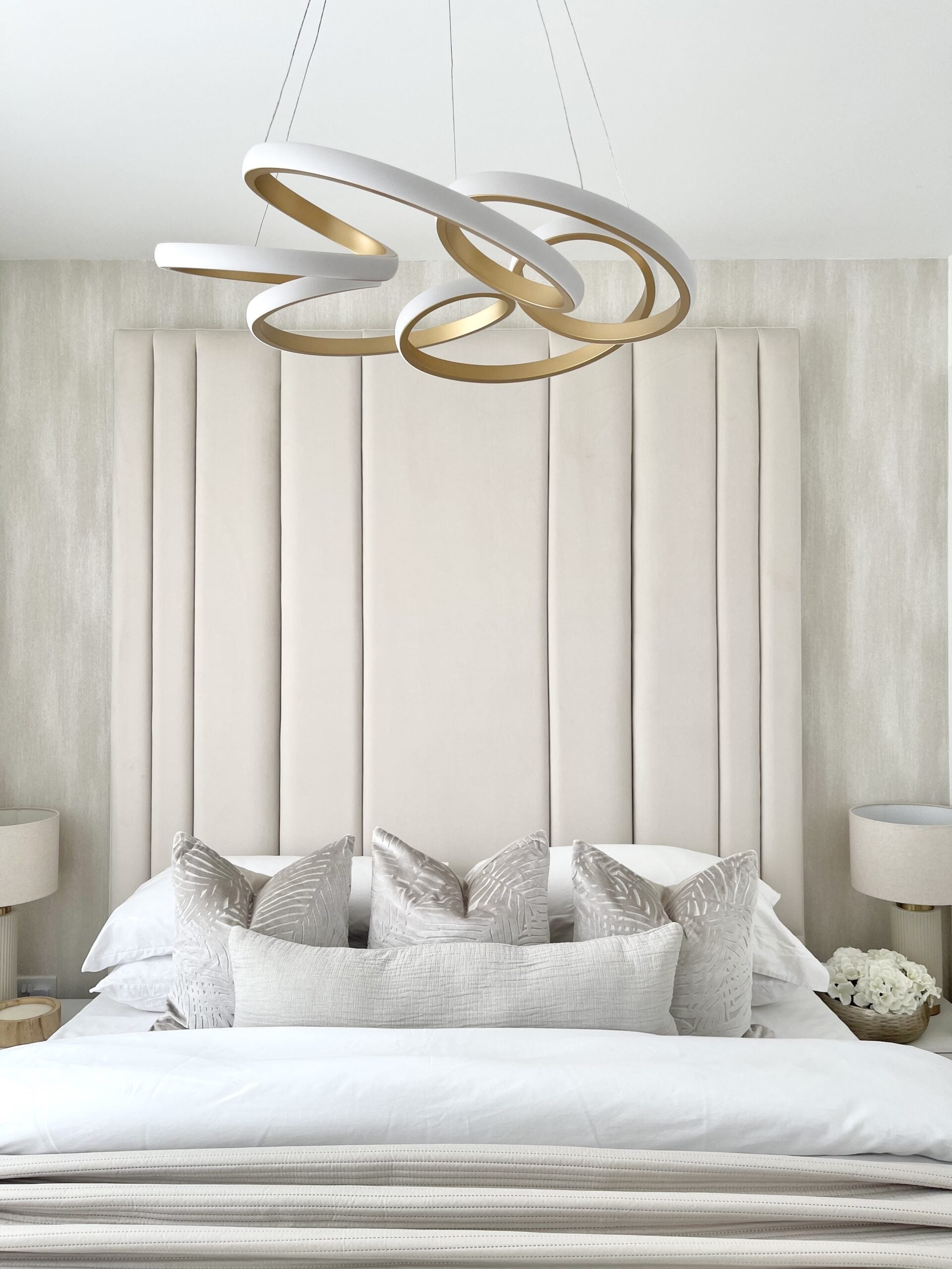 Upholstered double bed with tall headboard, modern pendant light, and neutral bedding