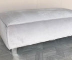 Modern rectangular light grey upholstered footstool with soft velvet texture on wood floor