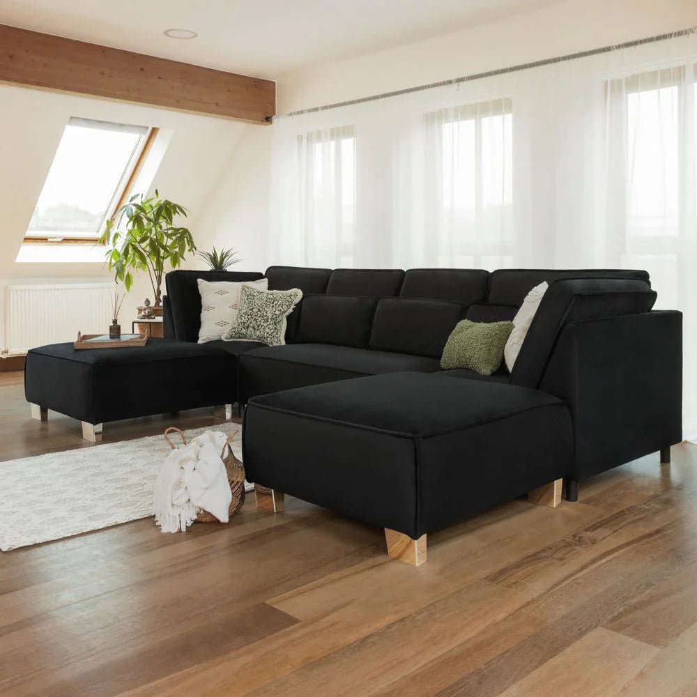 Modern black U-shape corner sofa with scatter cushions in a bright living room