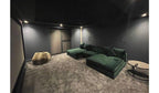 Large green cinema sofa in a modern home theater room with dark walls and plush carpet