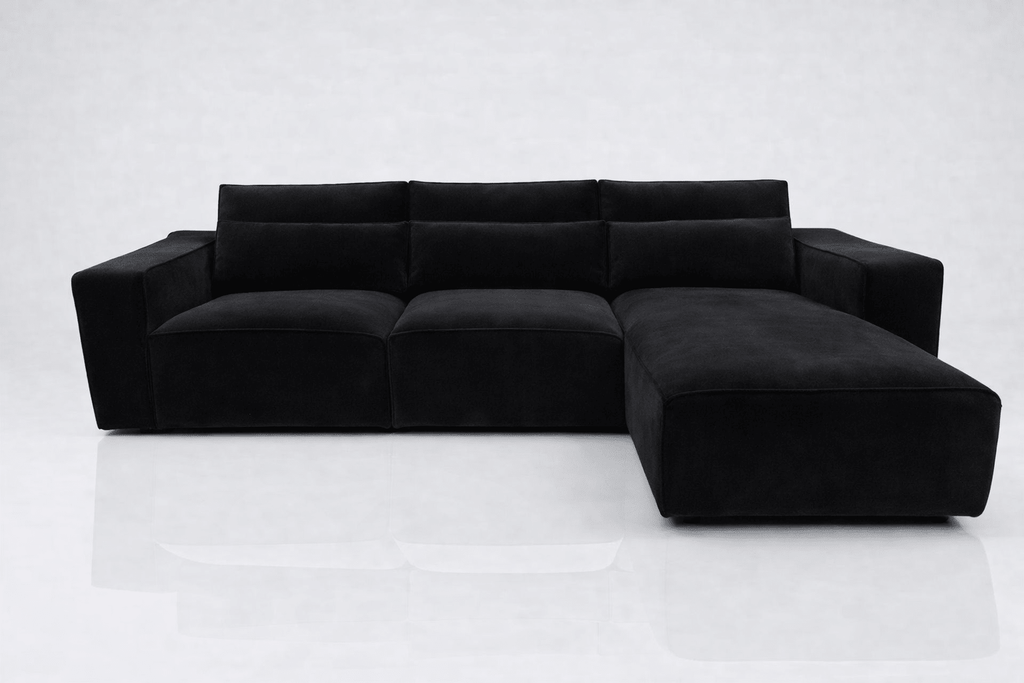 Modern black corner sofa with right-hand facing chaise and wide armrests on white background