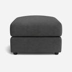Modern rectangular dark grey fabric ottoman footstool on a white background