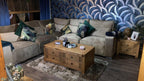 Modern grey corner sofa with botanical cushions and wooden coffee table in a cozy living room
