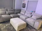 Modern grey corner sofa with matching footstool in a contemporary living room