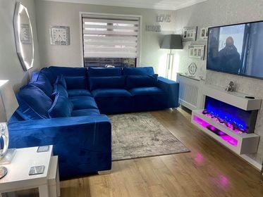 Blue corner sofa set in modern living room with wood floors and wall-mounted TV