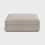 Modern cream fabric ottoman footstool with minimal design on a white background