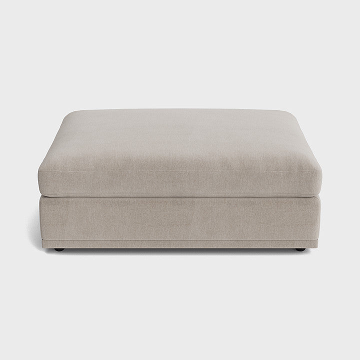 Modern cream fabric ottoman footstool with minimal design on a white background