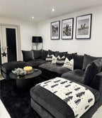 Large U-shaped charcoal sofa with patterned cushions and a festive throw in a modern living room.