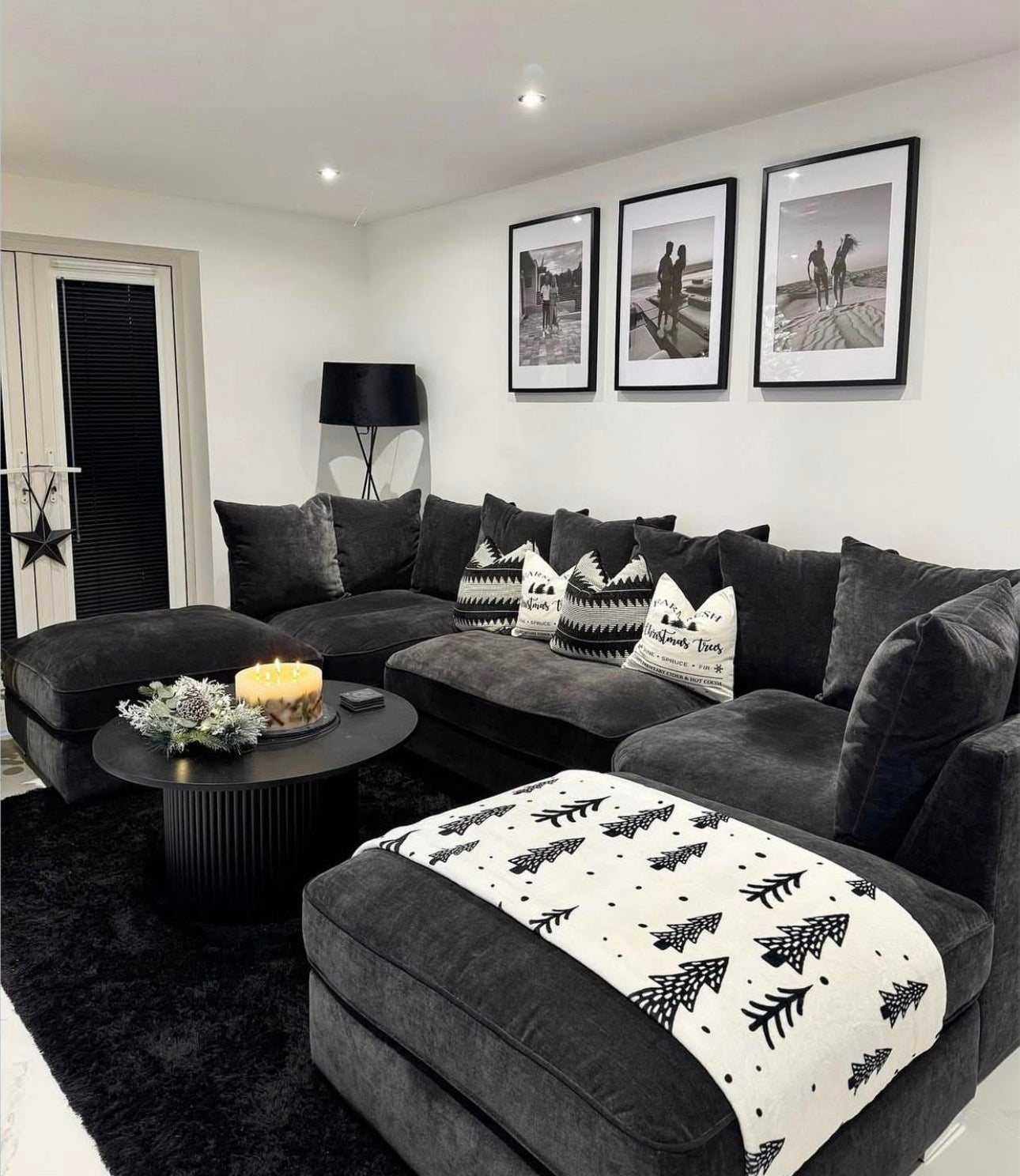 Large U-shaped charcoal sofa with patterned cushions and a festive throw in a modern living room.