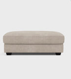 Modern beige fabric ottoman with low black legs on a white background